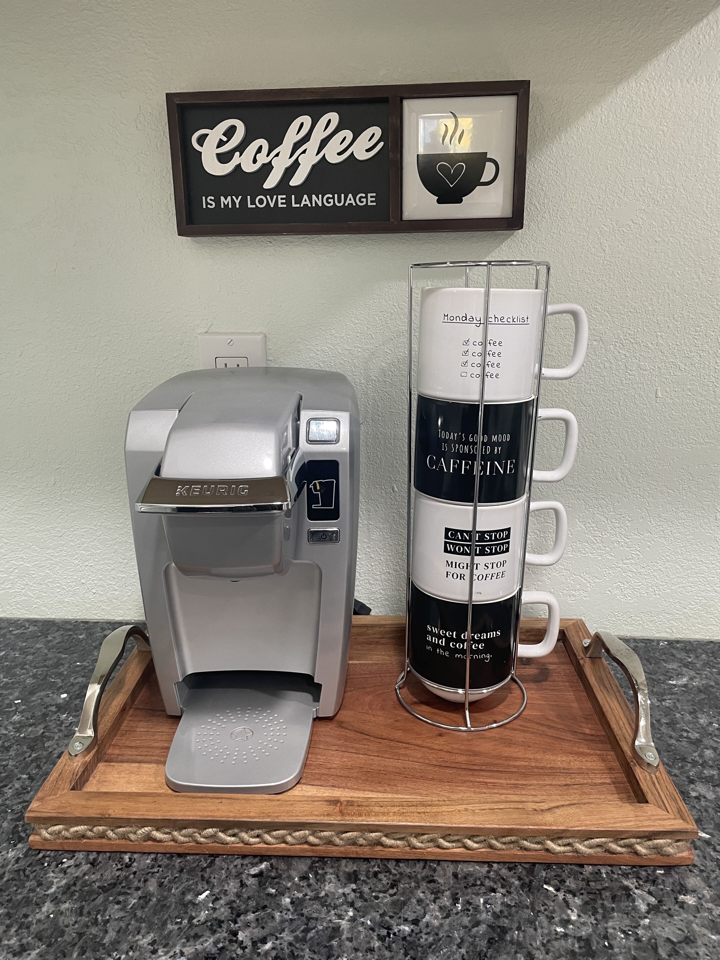A coffee maker on a tray with a mug of coffee and a sign above it that says "Coffee is my love language."