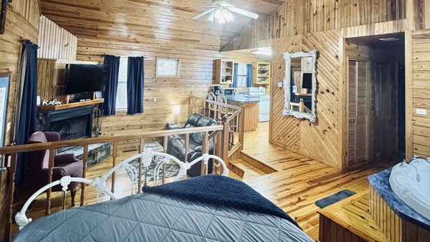 A cozy cabin interior with a wooden ceiling, a bed, a fireplace, a dining area, and a kitchen. - "The Sugar Shack" Cabin 2 (Oden)