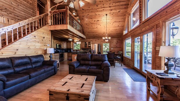 Un intérieur spacieux de chalet en bois, comprenant un salon, une salle à manger et une cuisine.