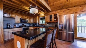 Une cuisine spacieuse dotée de meubles en bois, d’appareils électroménagers en acier inoxydable et d’un grand îlot central avec des tabourets de bar.