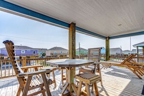 A wooden deck with a table and chairs, overlooking a row of colorful houses.