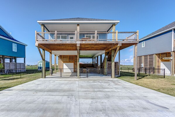 A two-story house with a balcony, a concrete driveway, and a fenced yard.