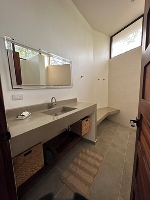 A modern bathroom with a dual sink vanity, a large mirror, and a built-in shower enclosure. - Modern Beach Home with Pool & Rooftop - 150 metros (Santa Cruz, Playa Avellanas)