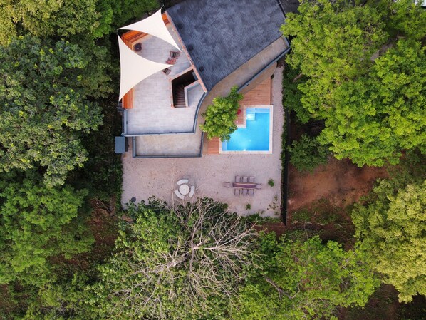 An aerial view of a house with a swimming pool, a patio with seating, and a large tree in the foreground. - Modern Beach Home with Pool & Rooftop - 150 metros (Santa Cruz, Playa Avellanas)