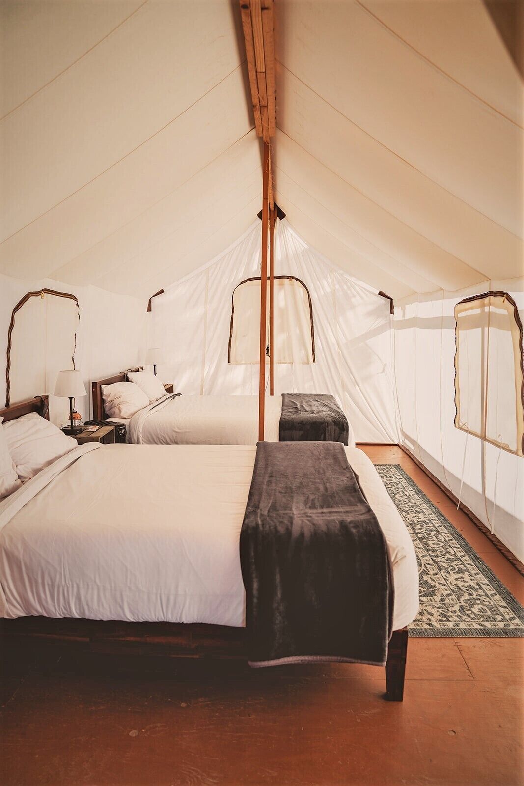 Una camera a tenda con un letto, comodini e una finestra.