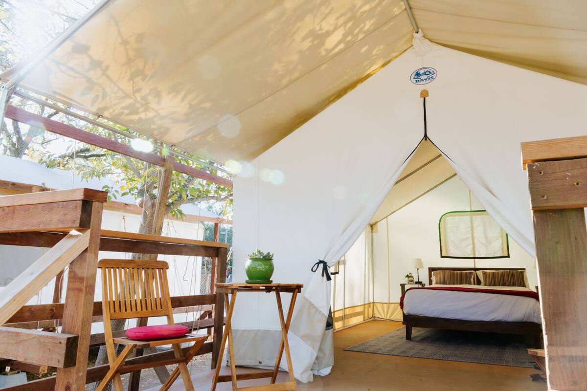 Een tent met een bed, een stoel en een kleine tafel.