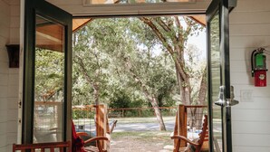 A wooden-framed door leading to an outdoor seating area with two wooden chairs and a bench. - Wildhaven Sonoma Glamping (Healdsburg)