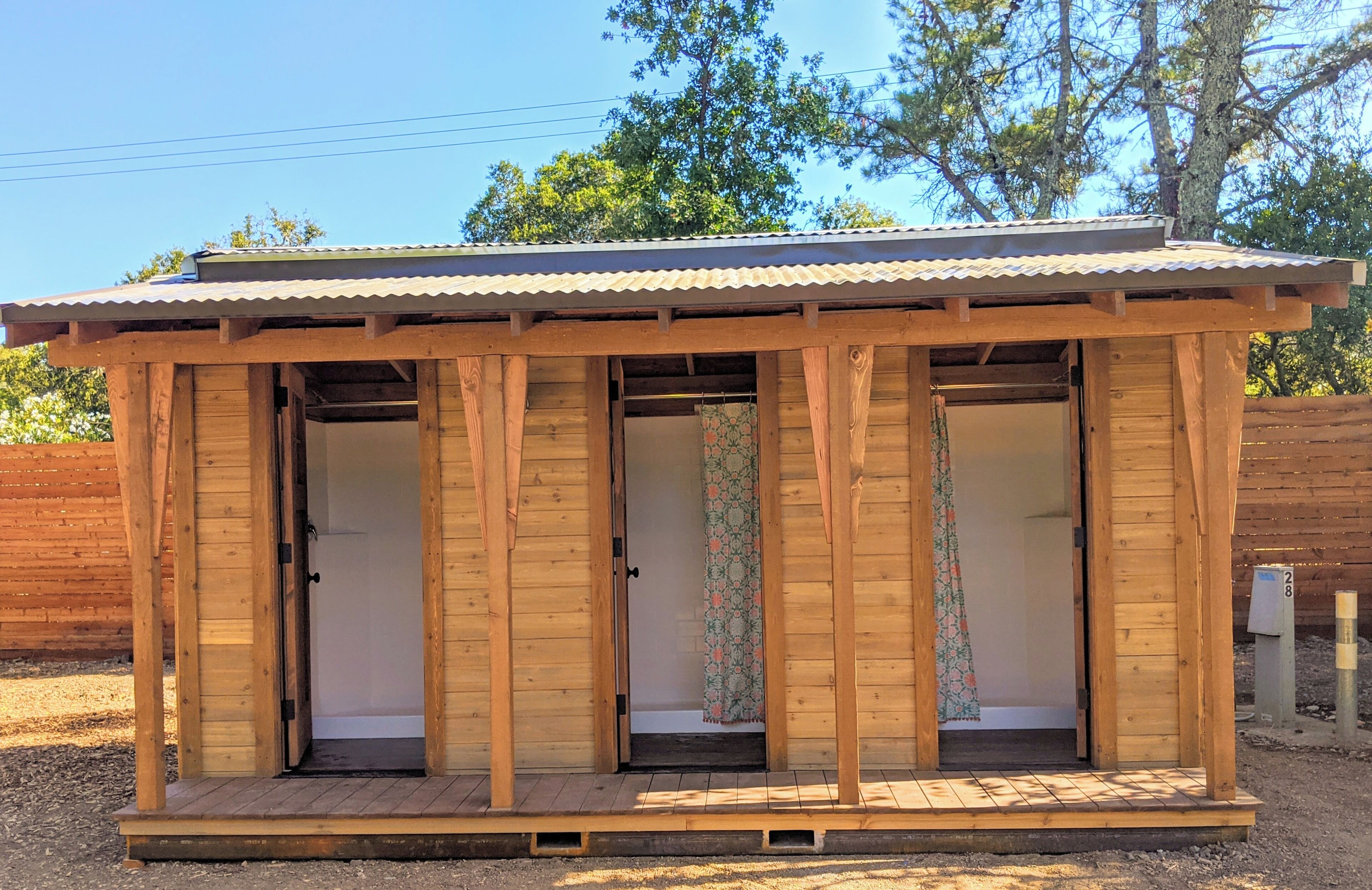 A small wooden cabin with a metal roof, two doors, and a small porch area.