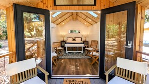 Une pièce confortable avec un lit, deux chaises, une table et un tapis.