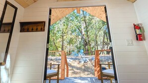 A wooden cabin with a sloped roof, a door leading to an outdoor deck, and a fire extinguisher mounted on the wall. - Wildhaven Sonoma Glamping (Healdsburg)