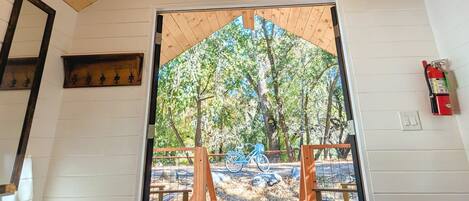 Uma cabana de madeira com telhado inclinado, porta que dá para um deck externo e um extintor de incêndio fixado na parede.