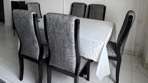 A dining area with a TV mounted on the wall, a table with a white tablecloth, and grey upholstered chairs. - VISTA AL MAR (Santa Marta)