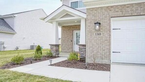 A two-story residential house with a brick facade, a garage, and a well-maintained lawn. - Newburgh Newsie - 3BR, 2.5BA, Gym, Patio, New Construction in Amazing Location! (Newburgh)