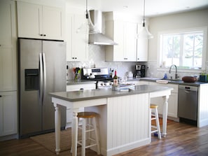 Enjoy cooking in this well-equipped kitchen with a central island, bar stools, and stainless steel appliances.