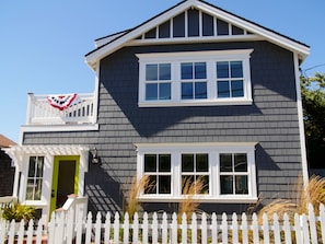 Enjoy the charming front porch with a picket fence, green door, and balcony.