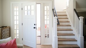 A staircase with wooden steps and white railings, leading to an upper floor. - Charming modern bungalow w/ hot tub steps away from the beach (Dillon Beach)