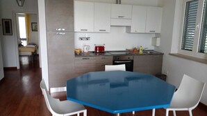 Une cuisine moderne avec des armoires blanches, une table bleue et une chaise blanche.