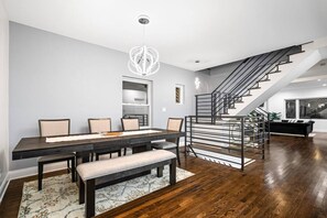 A modern dining area with a dark wood table and chairs, a bench, and a chandelier.