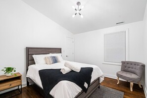 A bedroom with a bed, bedside table, chair, and a ceiling fan. - Stunning & Spacious 7BD Home with garage! (Chicago)