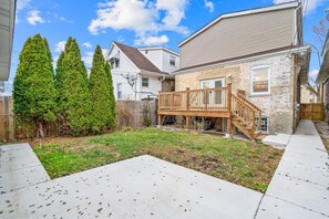 A residential backyard with a wooden deck, a fenced area, and a grassy lawn. - Stunning & Spacious 7BD Home with garage! (Chicago)