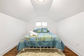 A bedroom with a bed, a window, and a white ceiling.