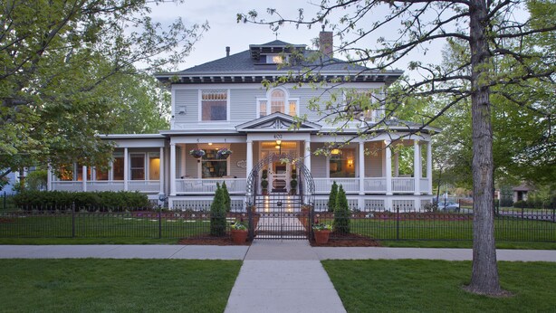 A two-story house with a front porch, a covered entryway, and a small garden area. - Edwards House (Fort Collins)