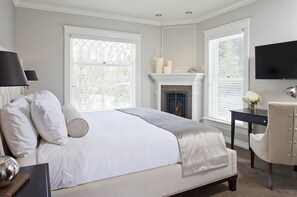 Cozy retreat with a large bed, fireplace, and workspace by the window.