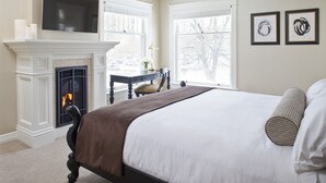 A bedroom with a fireplace, a bed, a desk, and two framed artworks. - Edwards House (Fort Collins)