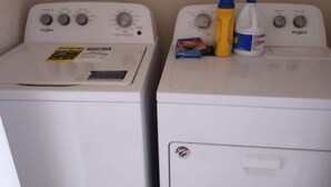 Dues rentadora Whirlpool blanques una al costat de l'altra, amb ampolles de detergent i una caixa a la part superior.