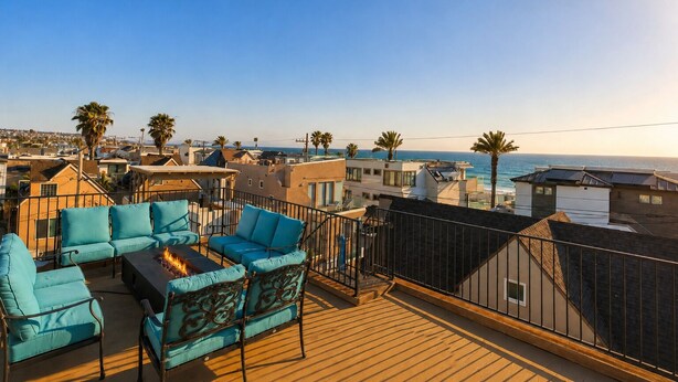 Una terraza en la azotea con mobiliario exterior, una chimenea y vistas al océano y edificios circundantes.