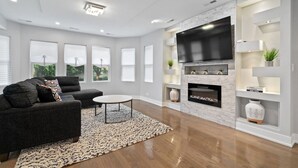A modern living room with a fireplace, a large TV, and a sofa.