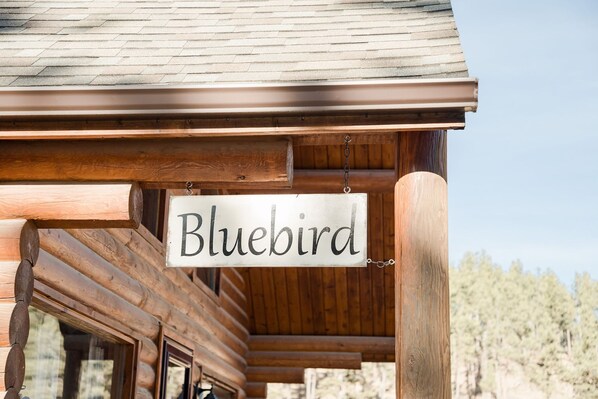 Une cabane en bois avec une enseigne portant le nom « Bluebird » suspendue au toit.