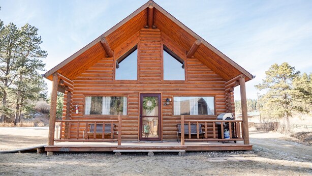 A log cabin with a porch, a front door, and a window.