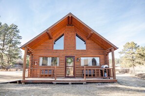 Une cabane en rondins avec une véranda, une porte d’entrée et une fenêtre.