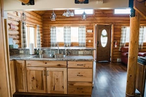 Cozy cabin-style interior with a fully equipped kitchen, wooden cabinets, and a comfortable seating area.