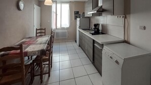 Una cocina compacta con mesa, sillas, cafetera y lavavajillas.