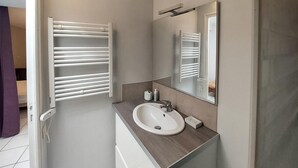 Un baño moderno con un lavamanos blanco, un espejo y un perchero para toallas.