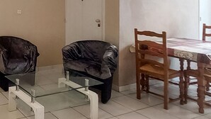 Un comedor con una mesa de vidrio y sillas, una mesa de madera con mantel blanco y una puerta con pomo decorativo.