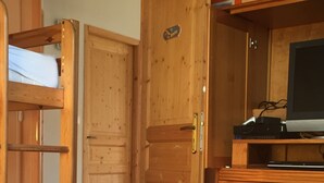Ein Zimmer mit einem Etagenbett, einem Holzschrank und einem Fernseher auf einem Holzboden.