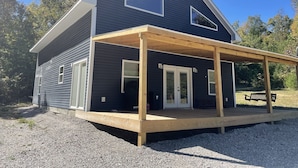 Ett tvåvåningshus med en mörk fasad, en träveranda och en inglasad veranda.