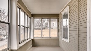 A covered porch with large windows, a wooden floor, and a view of a residential area. - Cheerful 4-Bedroom home in Midtown Omaha (Omaha)