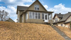 A two-story house with a steep front yard and a staircase leading to the entrance. - Cheerful 4-Bedroom home in Midtown Omaha (Omaha)