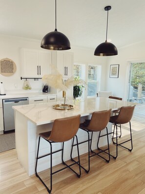 A modern kitchen with a central island, pendant lighting, and a view to the outdoors.