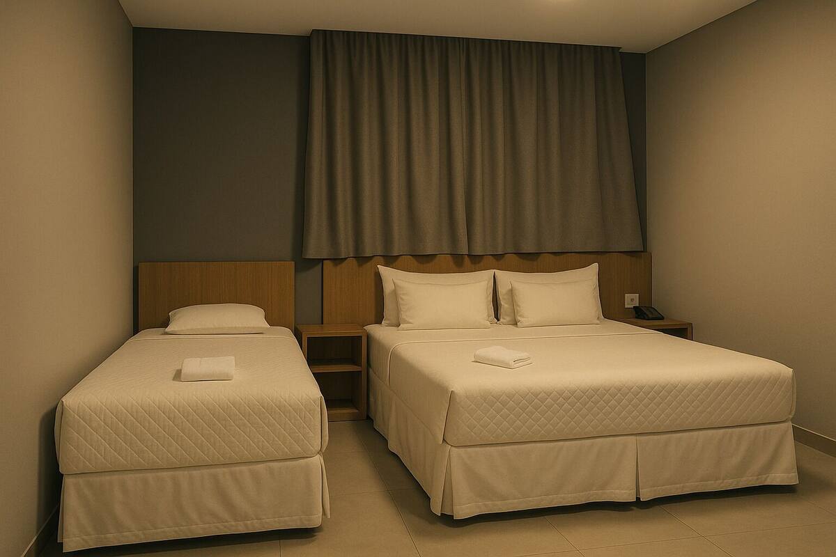 A hotel room with two beds, a nightstand, and a telephone.