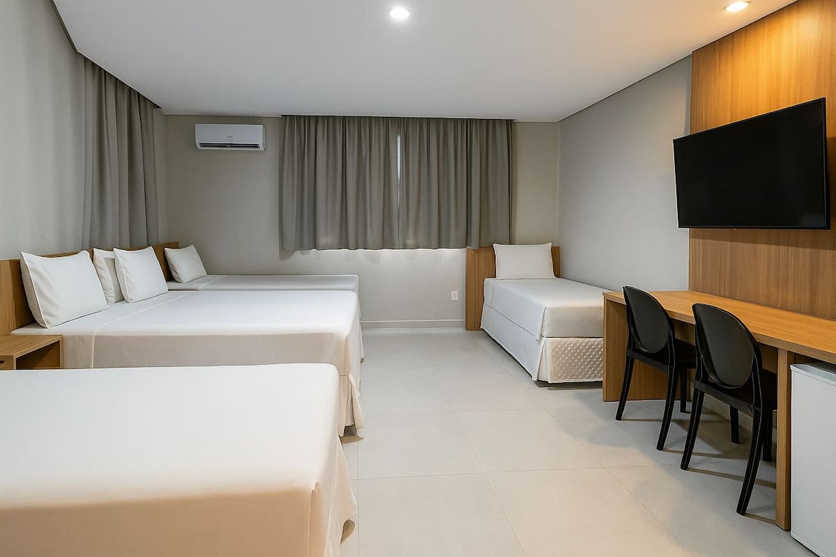 A hotel room with two beds, a desk, a chair, a TV, and a window with curtains.