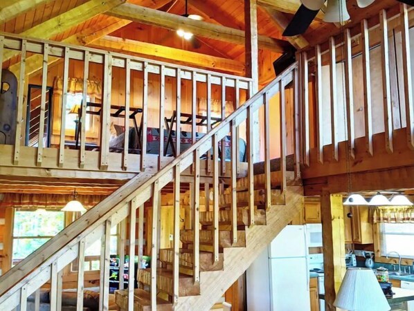 Cozy cabin with exposed beams and a rustic interior, featuring a central staircase and a kitchen with sink and countertop space.