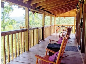 Guests can enjoy a seating area with a table and chairs on the deck, taking in the surrounding natural landscape.