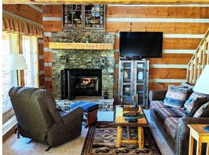 Cozy living room with a stone fireplace, flat-screen TV, and comfortable seating for relaxation.