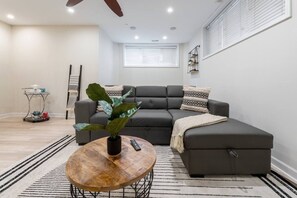 A modern living room with a sectional sofa, a coffee table, and a potted plant.