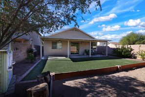 A two-story house with a covered patio, a fenced yard, and a small garden area.